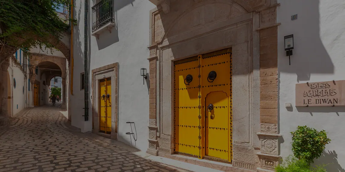 Ruelle pavée de la médina et portes jaunes cloutées de l'entrée de Dar El Jeld