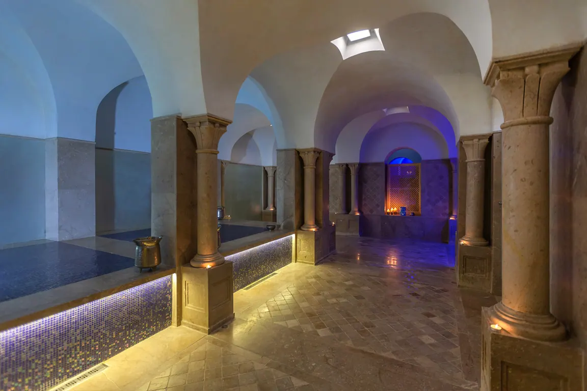 Hammam du spa avec colonnes de pierre, voûtes et bassin éclairé