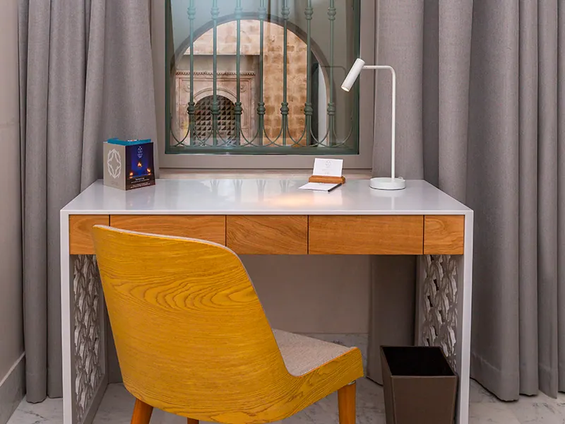 Wooden desk and yellow chair in front of a latticed window