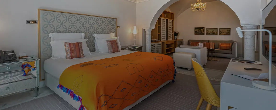 Suite Junior avec lit king size, plaid orange et coin salon sous une arche