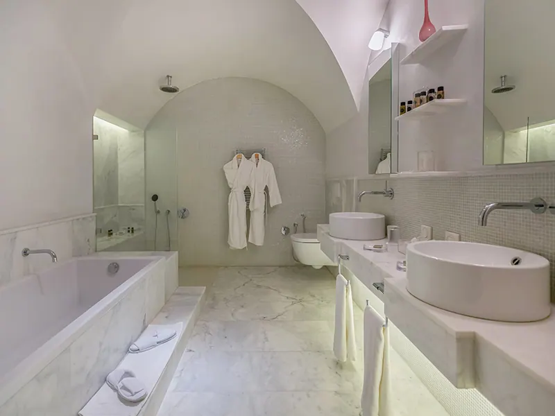 Marble bathroom with bathtub, round washbasin and bathrobes